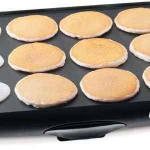 Young couple cooking together indoors using Ninja GR101, hood up grilling steaks, laughing and enjoying the moment, modern minimalist kitchen, realistic body language, shallow depth of field, cinematic lifestyle photography, very natural and relatable